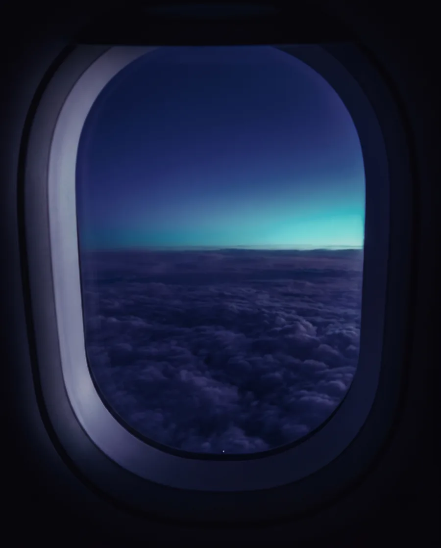 Vista da janela do avião sobre um mar de nuvens ao entardecer